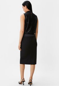 Schwarzes ärmelloses Oberteil mit Pailletten, hohem Kragen und rückseitiger Kerbe, kombiniert mit einem schwarzen knielangen Bleistiftrock und schwarzen High Heels Sandalen.