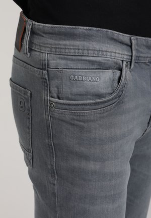 Gray denim jeans with a slim fit, featuring a visible logo, two side pockets, and a textured fabric, showing slight fading near the knees.