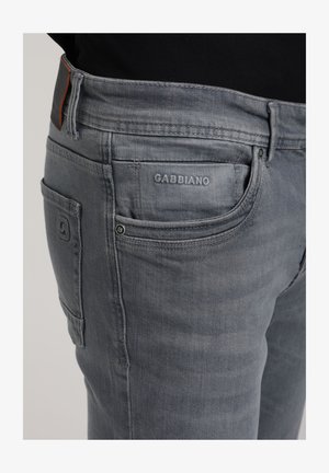 Jeans in denim grigio con vestibilità slim, dotati di un logo visibile, due tasche laterali e un tessuto testurizzato, con una leggera sbiaditura vicino alle ginocchia.