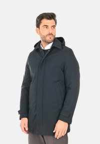 Cappotto navy con cappuccio, chiusura frontale con zip, due tasche laterali e taglio dritto. Realizzato in tessuto liscio e resistente all'acqua. Design minimalista.