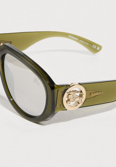 Πράσινα διαφανή υπερμεγέθη γυαλιά ηλίου με χρυσό λογότυπο στα πλαϊνά και ελαφρώς σκουρόχρωμους φακούς. Λεία υφή και ξεκάθαρο σχήμα.