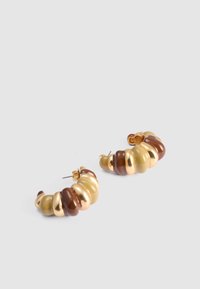 Gouden en bruine oorringen in de vorm van een ring met een ribbelontwerp en afwisselend glanzende en matte afwerkingen. De gestructureerde oppervlakte voegt diepte toe.