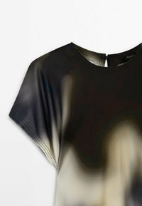 Blouse courte à manches courtes noire et beige avec encolure ronde et fermeture à boutons dans le dos, présentant un motif de tissu lisse en dégradé.