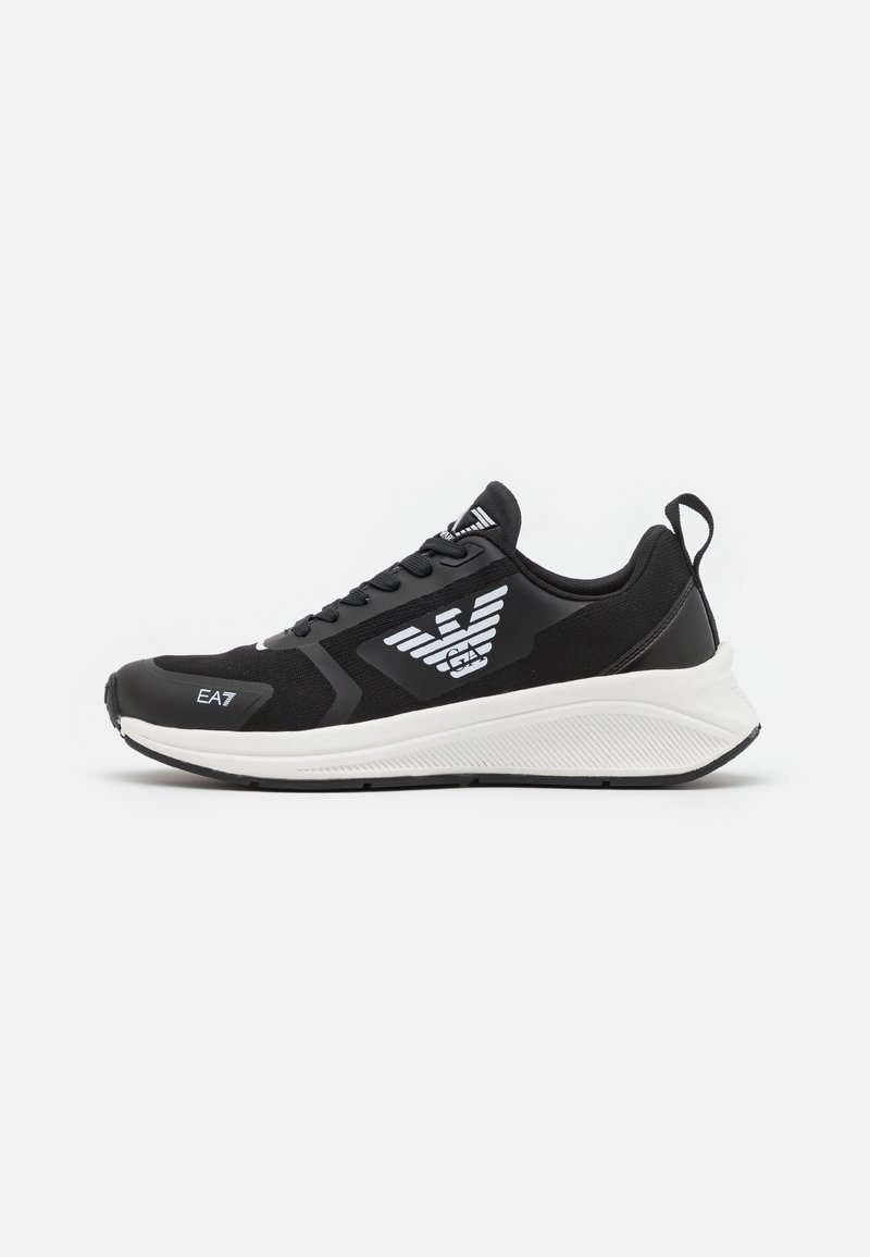 Baskets sportives noir et blanc avec un design à lacets, logo EA7 sur le côté et la languette, et une semelle blanche épaisse avec languette au talon.