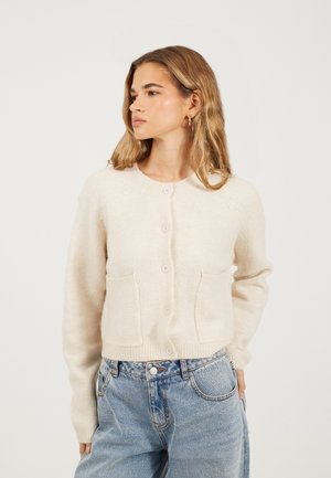 Hellbeige gestrickte Strickjacke mit langen Ärmeln, Rundhalsausschnitt und Knopfverschluss. Verfügt über zwei vordere Taschen und einen gerippten Saum.