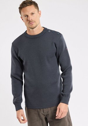 Ciemnoszara dzianinowa sweter z okrągłym dekoltem, długimi rękawami i trzema guzikami na ramieniu. Gładka tekstura, prosta forma.