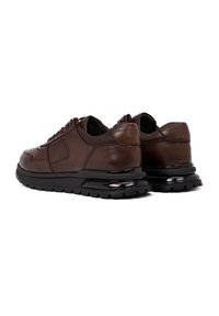 Bruine leren sneakers met een gestructureerde afwerking, zwarte rubberen zool en gewatteerde kraag. Voorzien van veters en gestikte details aan de zijkanten.