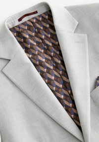 Blazer gris claro con solapas con muesca, que presenta un forro geométrico de patrones marrón y púrpura y un detalle de bolsillo en el pecho.