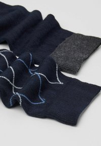 Ciemnoniebieskie i antracytowe dziane skarpetki z teksturowanym wzorem, ozdobione jasnoniebieskimi i białymi akcentami. Miękki, elastyczny materiał.