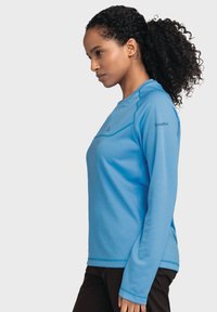 Hellblaues Langarmshirt mit Rundhalsausschnitt, kontrastierenden Nähten und Logo am rechten Ärmel. Hergestellt aus einem glatten, dehnbaren Material.