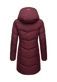 Vyno raudonos spalvos pūsta striukė su gaubtu, puošta chevron tipo siuvimu, ilgomis rankovėmis ir išlenkta apačia. Patvari medžiaga su lygiu paviršiumi.