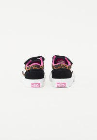 Sneakers in suede nero e stampa leopardata con suole in gomma bianca, dettagli in rosa e cinturini in Velcro. Presentano il logo Vans sul tallone.