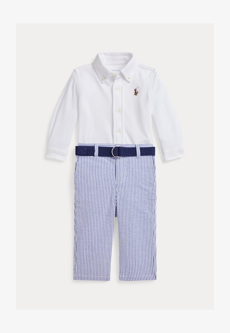 Chemise blanche à manches longues avec col à boutons, associée à un pantalon rayé bleu et blanc et une ceinture bleu marine, avec un petit logo sur la poitrine.