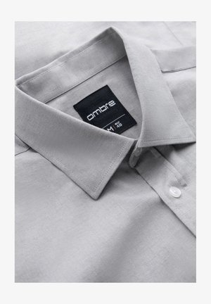 Chemise à boutons gris clair avec un motif texturé en chevrons. Elle possède un col et une étiquette affichant "ombre", taille M, EUR 48.