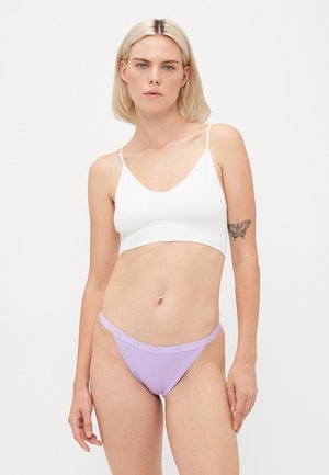Bralette bianco con spalline sottili e scollatura a V profonda, abbinato a un perizoma a vita bassa lavanda con fascia logo. Texture liscia, design minimalista.