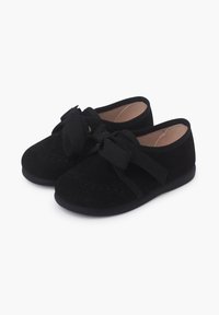 Pantofi din suede negru cu vârf rotund, având un detaliu din material sub formă de fundă și un design cu curea încrucișată. Textură netedă, talpă solidă din cauciuc negru.