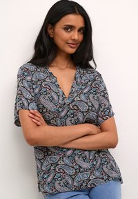 Īsām piedurknēm ir blūze, kas raksturojas ar melnu fonu un paisley rakstu zilā, rozā un baltā krāsā. V-veida kakla dizains un brīvs piegriezums.