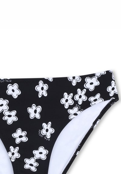 Bas de bikini noir avec motif floral blanc, présentant des formes de fleurs arrondies, une texture lisse et une doublure intérieure blanche.