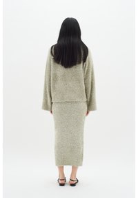 Tvådelad outfit bestående av en mjuk, ljusgrön fluffig stickad jacka med vida ärmar och en matchande lång kjol. Enkel design, utan synlig hårdvara.