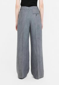 Wide-leg trousers in a textured gray fabric. Features a flat waistband and a rear pocket with a button closure.