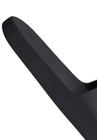 Poignée en caoutchouc noire avec logo Jack Wolfskin en relief et empreinte de patte, inclinée sur un fond blanc.