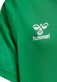 Grøn sports T-shirt lavet af glat stof, med et hvidt logo "hummel" og et stiliseret bi-design på brystet. Enkel design, korte ærmer.