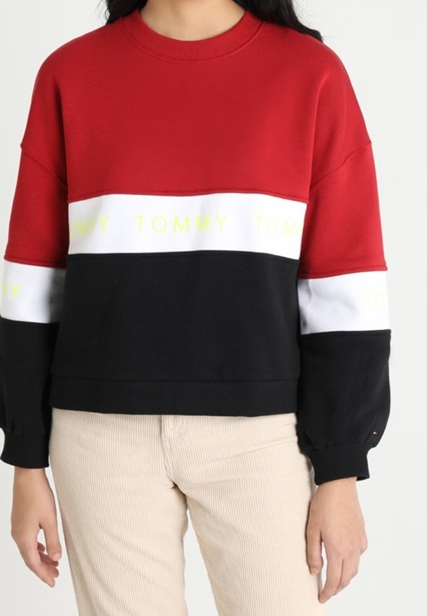 Felpa oversize rossa, nera e bianca con testo giallo "TOMMY". Presenta un collo a giro e maniche lunghe con polsini a coste.