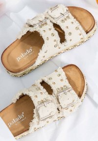 Cremfarbene Leinensandalen mit zwei Riemen, die mit Schnallen verziert sind, geschmückt mit Faux-Juwelen und einer geflochtenen Jutesohle. Weicher, strukturiert Fußbett für Komfort.