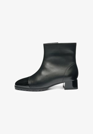 Schwarze Knöchelstiefel aus glattem Leder mit einer Lackleder-Zehenkappe, Blockabsatz und strukturiertem Fußbett. Einfaches, elegantes Design mit minimalen Nähten.