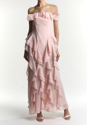 Różowa sukienka odkrywająca ramiona, z warstwowymi falbanami, lejącym się materiałem i dopasowanym gorsetem. Gładka faktura i długość do kostek, noszona z sandałami.