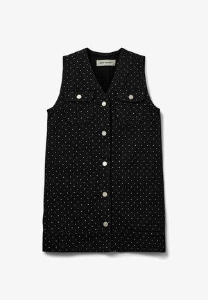 Fekete farmer mellény fehér pöttyökkel, két elülső zsebbel, gombos záródással és ujjatlan kialakítással. Texturált anyag, hétköznapi stílus.