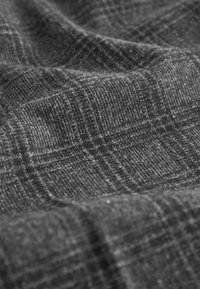 Tissu gris texturé avec un motif à carreaux, présentant une surface douce et tissée ainsi que des variations subtiles de teintes.