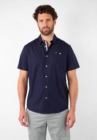 Chemise boutonnée à manches courtes de couleur marine avec des accents blancs, une poche poitrine et un tissu lisse. Comprend des boutons sur le devant et un col standard.