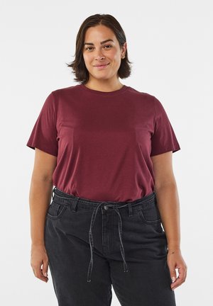 T-shirt bordeaux a maniche corte in cotone morbido, con scollo a girocollo. Abbinato a jeans neri a vita alta con coulisse.