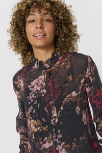 Blusa nera trasparente con stampa floreale multicolore, scollatura arricciata e chiusura con bottoni. Maniche lunghe con polsini arricciati.