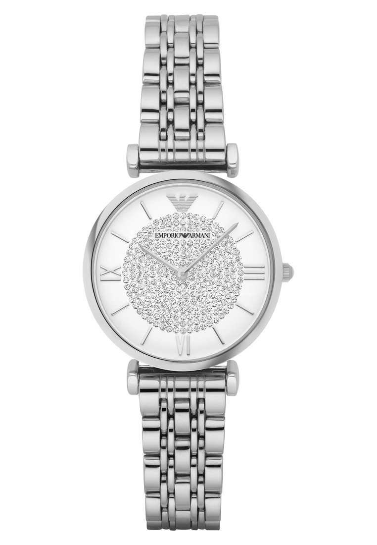 Silberner Edelstahl-Uhr mit rundem Zifferblatt, einem weißen Ziffernblatt mit einem krystallverzierten, kreisförmigen Muster und römischen Ziffern als Stundenmarkierungen.