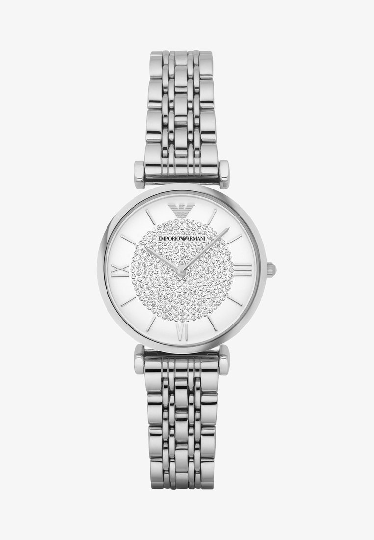 Silberner Edelstahl-Uhr mit rundem Zifferblatt, einem weißen Ziffernblatt mit einem krystallverzierten, kreisförmigen Muster und römischen Ziffern als Stundenmarkierungen.