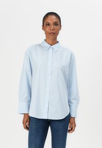 Camicia button-up a righe blu chiaro e bianche con colletto, maniche lunghe e una vestibilità rilassata. Presenta una texture liscia e maniche con polsini.