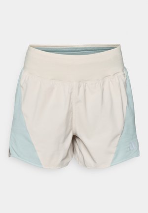 Shorts de sport beige clair avec une large ceinture élastique et des panneaux latéraux texturés bleu clair. Présente un petit logo à l'ourlet.
