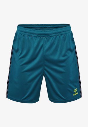 Pantalones cortos deportivos color azul verdoso con cinturilla elástica, rayas en zigzag negras y grises en los costados, y pequeño logo amarillo de Hummel en la pierna izquierda.
