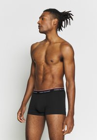 Sorte boksershorts med en logo livlinje i rødt og hvitt. Glatt bomullsstoff, tettsittende design og midt på låret lengde.