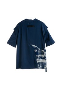 Camisa de manga corta azul marino con un panel texturizado asimétrico blanco y azul en la parte inferior derecha y un pequeño parche rectangular negro cerca del cuello.