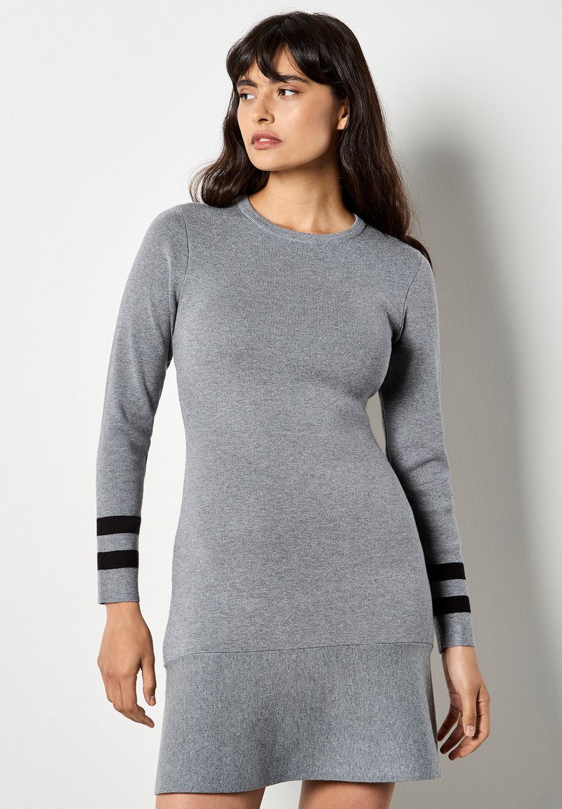 Graues Langarmkleid mit tailliertem Oberteil und ausgestelltem Saum. Verfügt über dunkle gestreifte Akzente an den Ärmeln und besteht aus einem weichen Strickstoff.