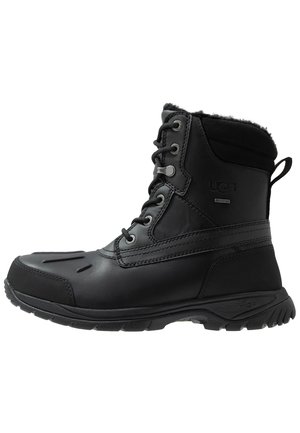 Botte d'hiver isolée noire avec laçage à l'avant, semelle robuste et doublure douce au col, conçue pour temps froid et usage extérieur.