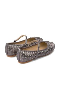 Zapatos planos de metal gris con una correa, adornados con tachuelas plateadas redondas, con punta redondeada y superficie texturizada.
