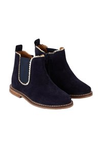 Bottines en daim bleu marine avec festons dorés, panneaux élastiques sur le côté et fermeture éclair ; semelle plate marron avec détails de couture.