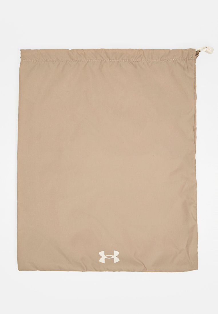 Bolsa de drawstring color beige con el logo de Under Armour en blanco centrado cerca de la parte inferior, tela lisa y borde superior cosido con cierre de cuerda ajustable.