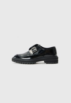 Black shiny leather loafer with a silver buckle strap and thick rubber sole with tread, shown in profile on a white background.