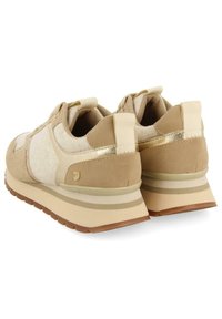 Baskets de sport beiges avec un mélange de tissus texturés, y compris du daim et du feutre. Présentent des accents métalliques et une semelle empilée rembourrée.