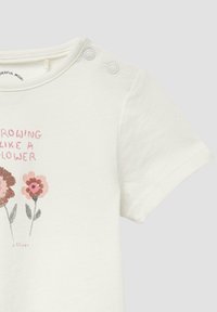 Weißes Baumwoll-T-Shirt mit rundem Ausschnitt und Druckknöpfen. Das bedruckte Design zeigt pinkfarbene und braune Blumen mit dem Text "WACHSEN WIE EIN BLUME."